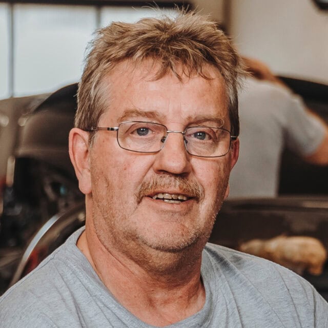 Handwerker in Werkstatt lächelt in Kamera