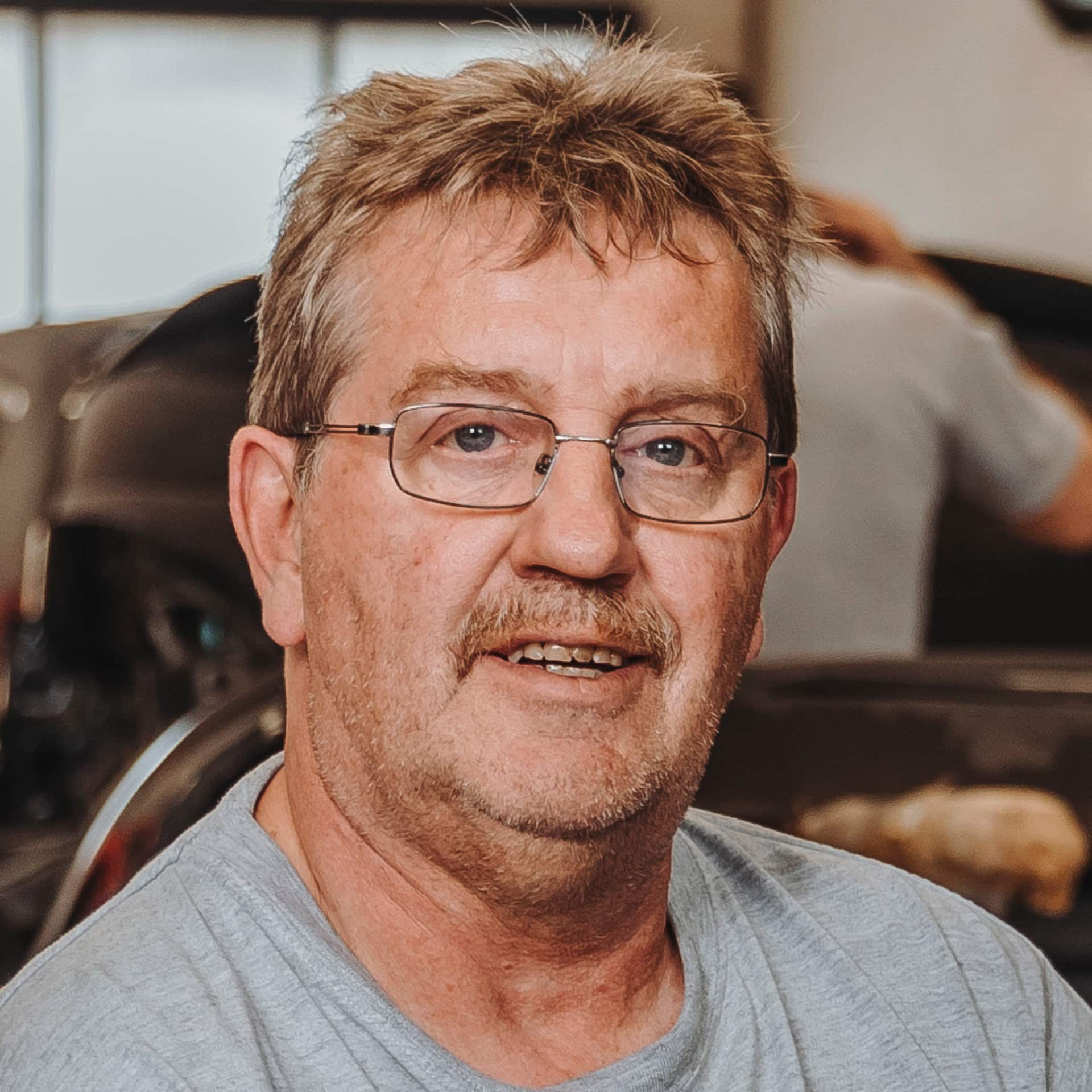 Handwerker in Werkstatt lächelt in Kamera